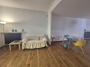 A living area with a sofa, a small table, a lamp, and a dining table with chairs. - Mondello Villa Nereidi - Rooms & Garden (Palermo)