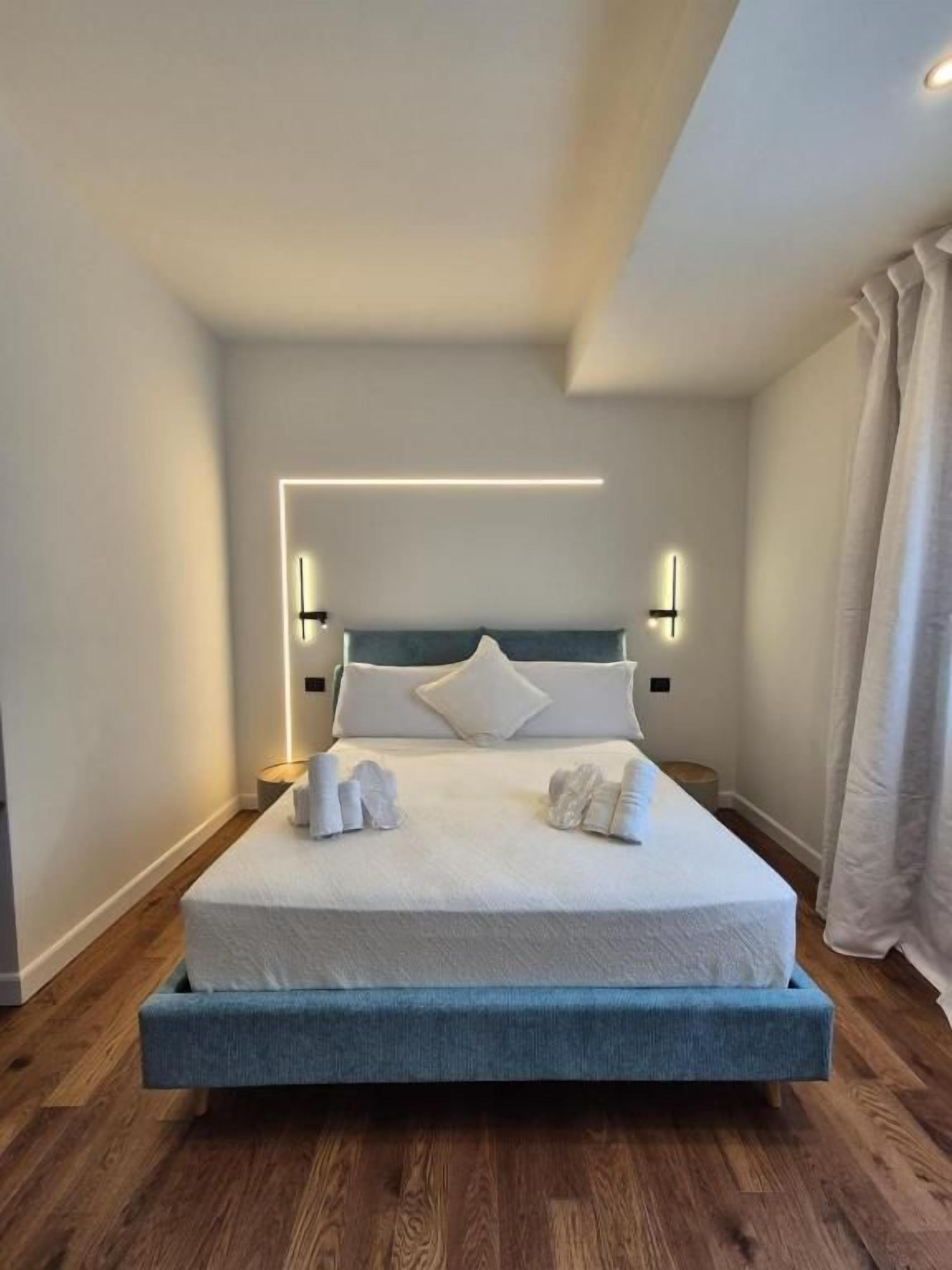 A modern hotel room with a large bed, bedside lamps, and a wooden floor.