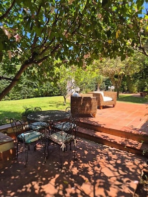 An outdoor patio with a table and chairs, a wicker sofa, and a brick pathway. - Mondello Villa Nereidi - Rooms & Garden (Palermo)