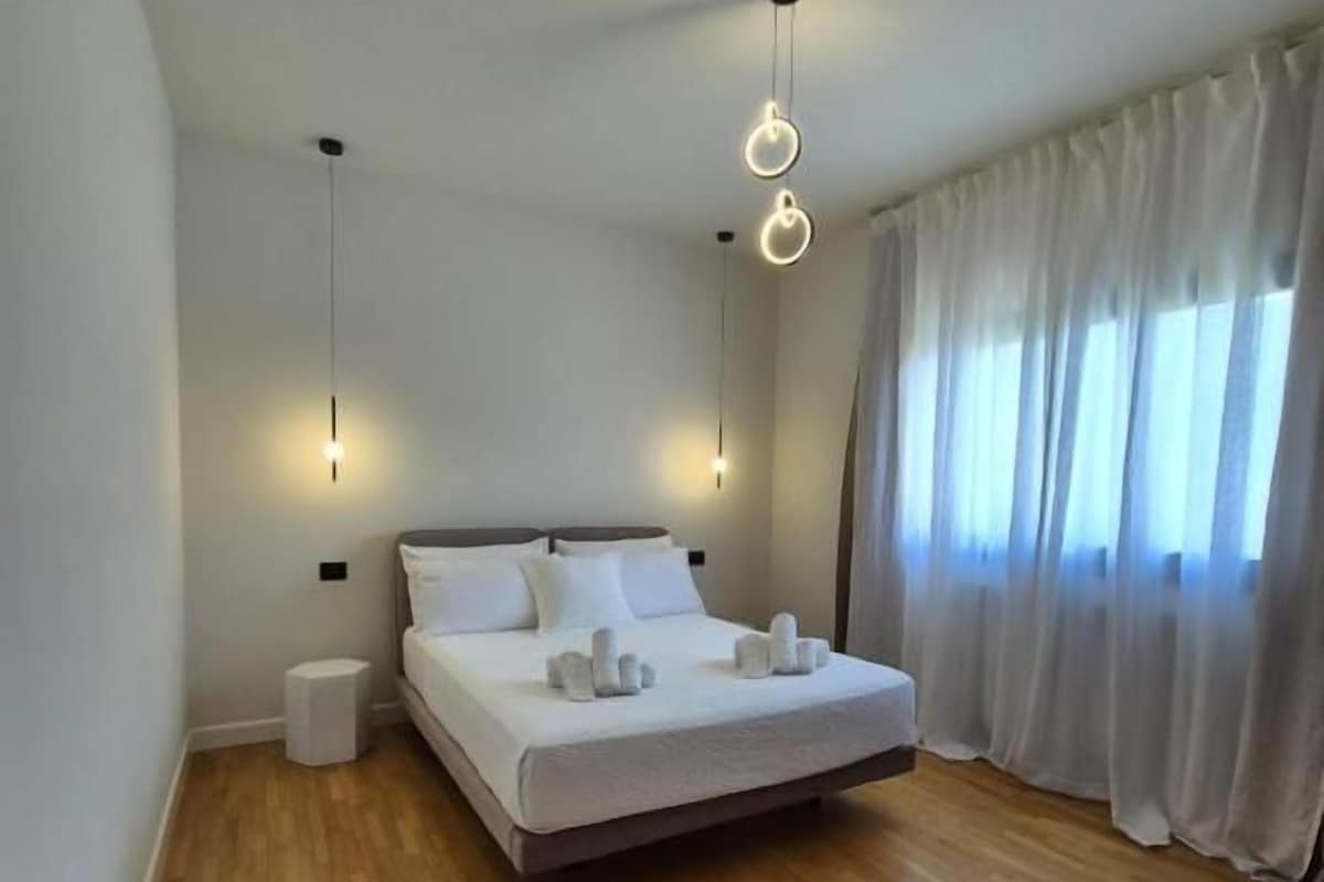 A bedroom with a bed, bedside tables, a chair, and a window with curtains.