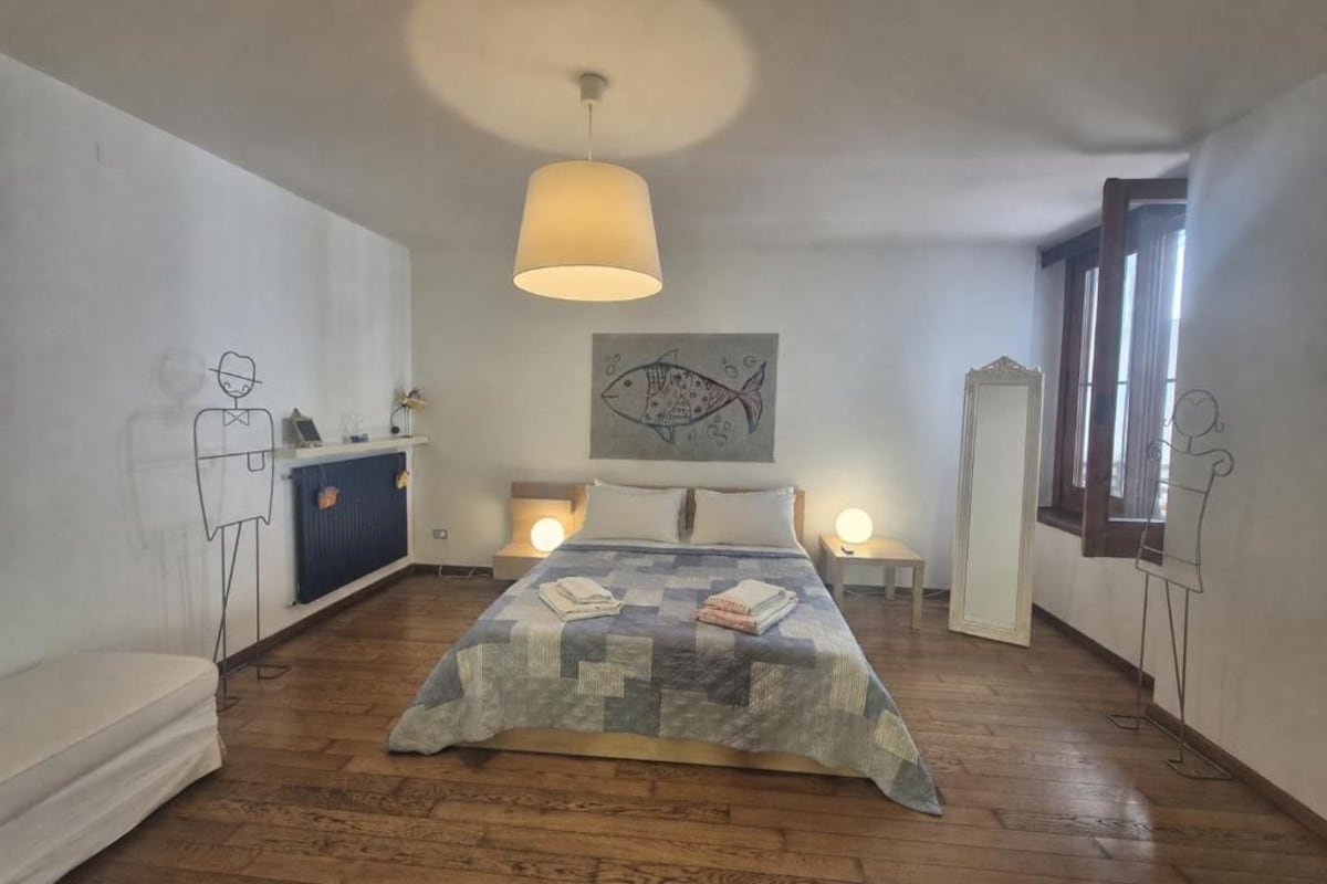 A bedroom with a bed, bedside tables, a lamp, a radiator, and a window.