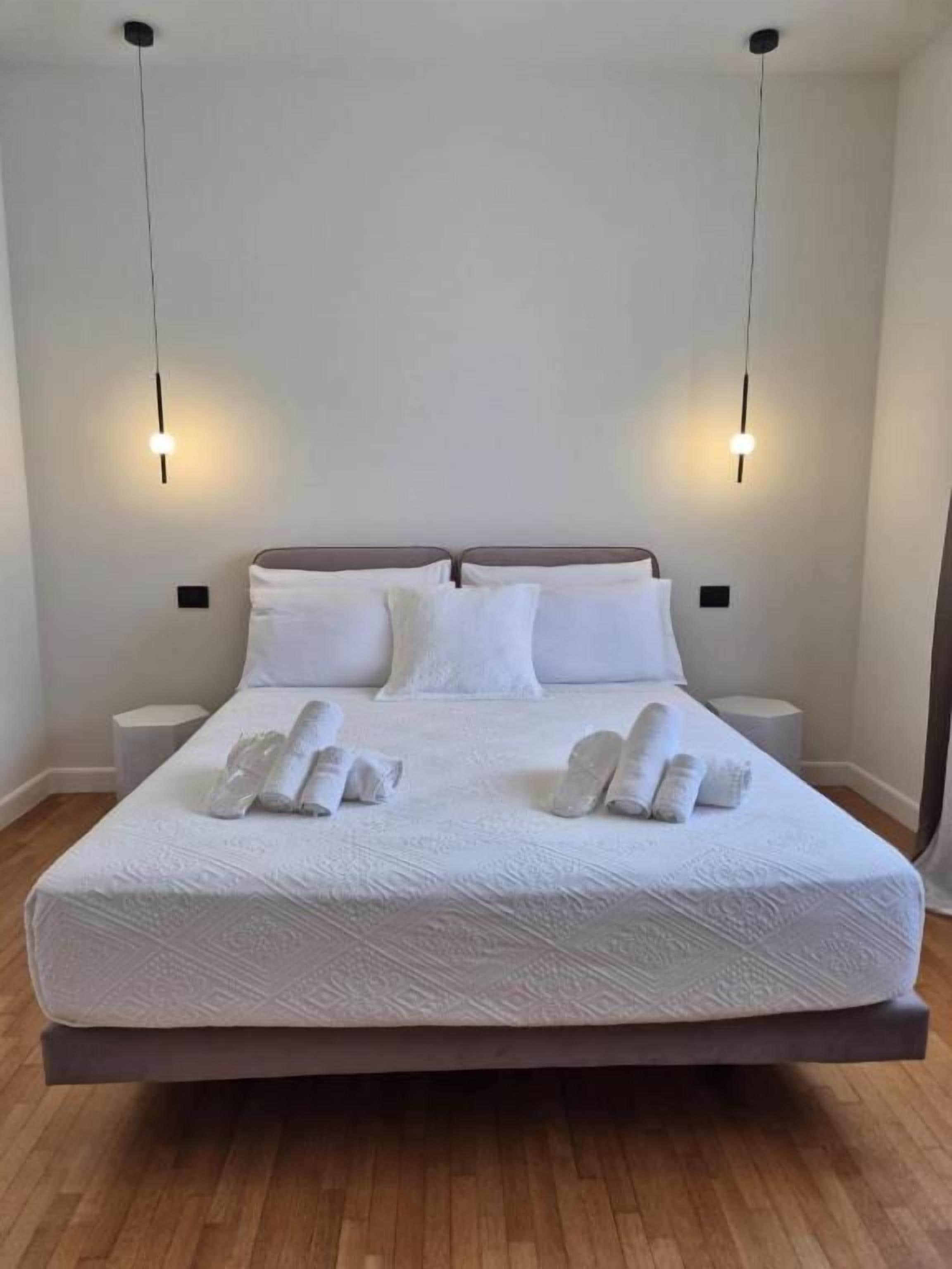 Un lit recouvert d’une couvre-lit blanche, deux lampes de chevet et des serviettes soigneusement pliées.