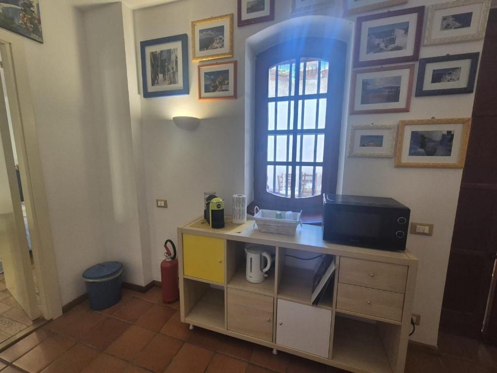 A room with a window, a microwave, a small cabinet, and a trash bin.