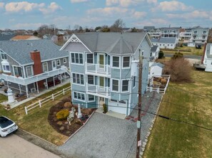 A multi-story residential building with a balcony, a driveway, and a small garden area. - The Salty Escape (Narragansett)
