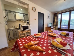 A room with a dining table set for a meal, a kitchenette, and a window with a view. - 50m from ski slopes, 7th floor, balcony, tv, ski locker, 53m², Vars (Vars)