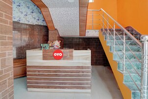 Bancada de recepção com uma placa indicando 'OYO' em um interior moderno, com escada e azulejos decorativos.