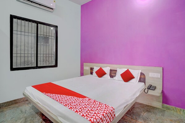 A hotel room with a bed, a window with bars, a phone, and a wall with a purple color.