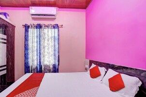 Quarto com cama, guarda-roupa, cortina e aparelho de ar condicionado.