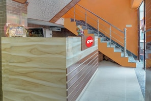 A reception desk with a sign, a staircase, and a tiled floor.