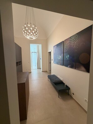 A modern interior with a bench, artwork, and a pendant light. - Alkimia Luxury Rooms (BRINDISI)