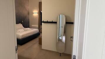 A hotel room with a bed, a mirror, and a door.