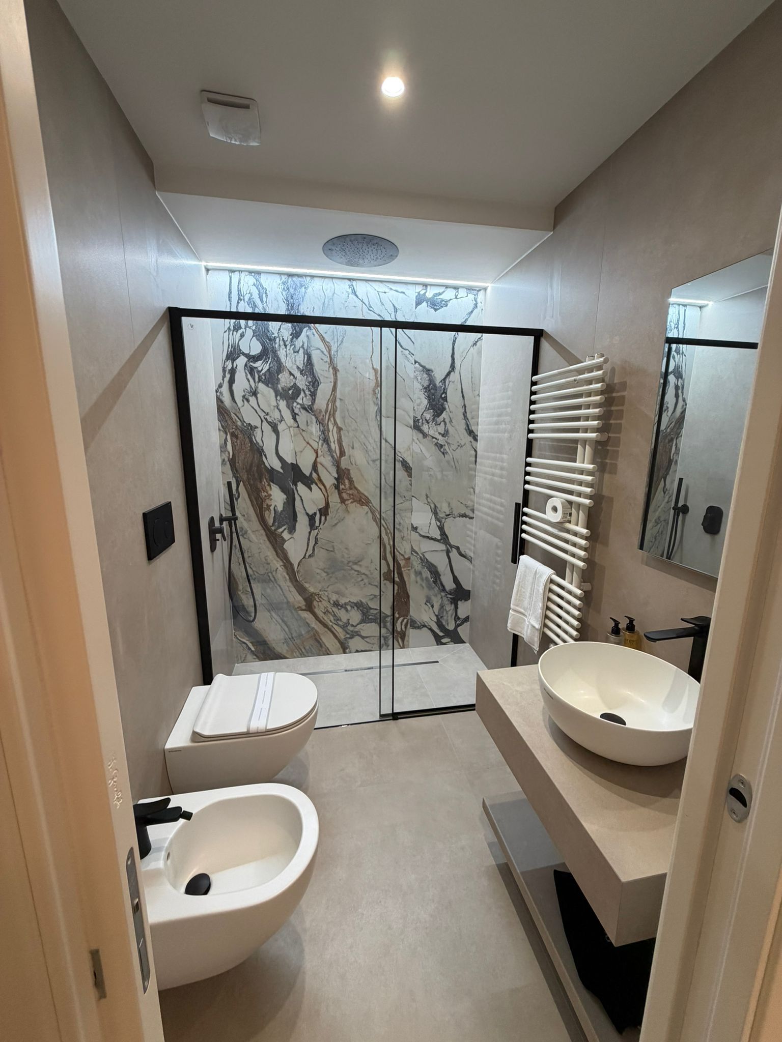 Un baño moderno con dos lavamanos, ducha y pared de mármol.
