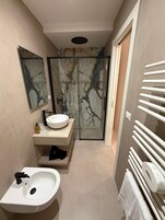 Un baño moderno con lavamanos blanco, un espejo y cabina de ducha de vidrio.