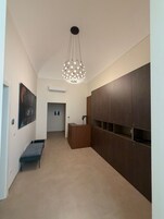 Un pasillo con una lámpara colgante moderna, un banco y un armario con estantes.