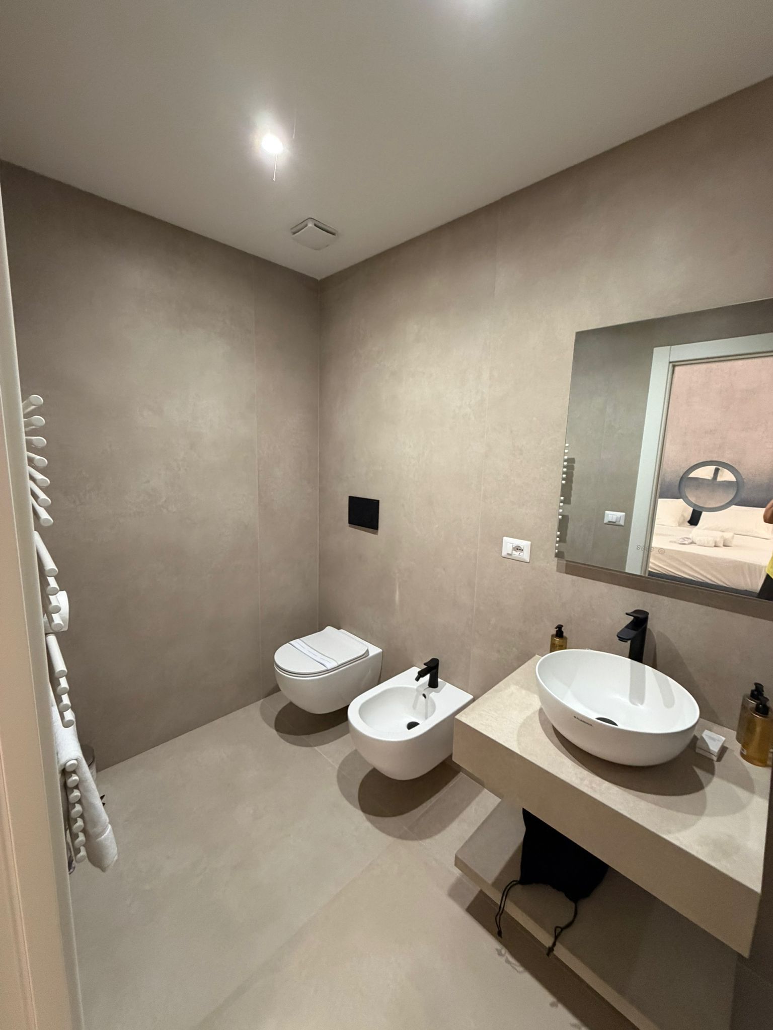 Een moderne badkamer met toilet, bidet en een groot wastafelmeubel met spiegel.