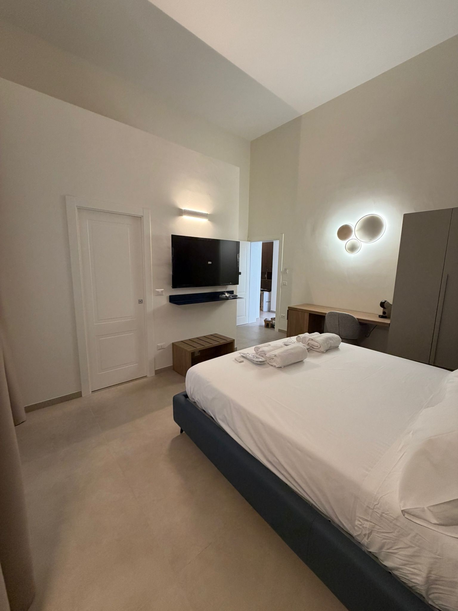 A hotel room with a bed, a television, a desk, and a wardrobe.