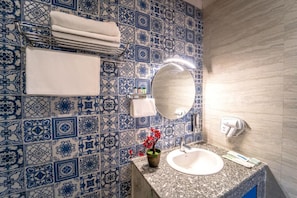 A bathroom with a sink, mirror, towel rack, and a decorative tile wall. - The Neeraj Ganga Cottages  (Rishikesh)