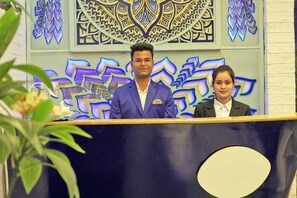 A man and a woman standing behind a podium with a decorative background. - The Neeraj Ganga Cottages  (Rishikesh)