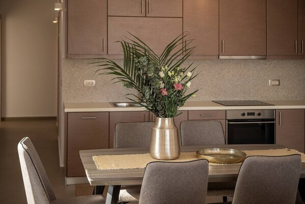 Eine moderne Küche mit Holzausstattung, einem Esstisch mit Stühlen und einer Vase mit Blumen.