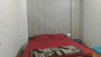 Quarto individual com parede estampada, colcha vermelha e manta com estampa de leopardo.