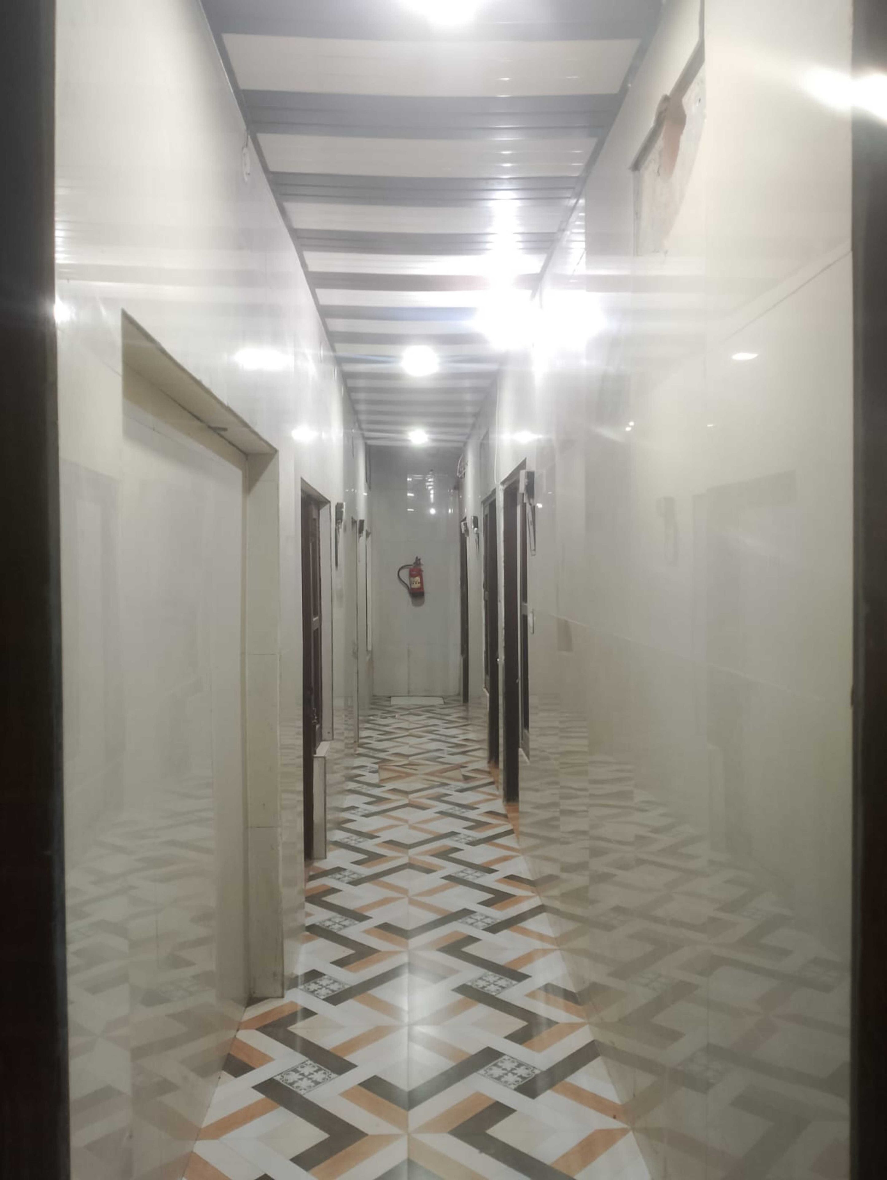 Un pasillo con suelo estampado, puertas a ambos lados y un techo con iluminación empotrada.
