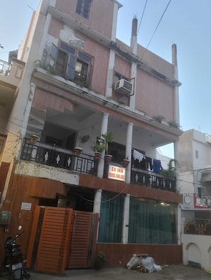 A multi-story building with balconies, a sign indicating rooms are available, and a visible entrance gate. - SV Inn Hotel (Lucknow)