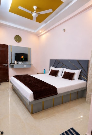 Ein Schlafzimmer mit Bett, Deckenventilator, Wand-Fernseher und einer Wanduhr.