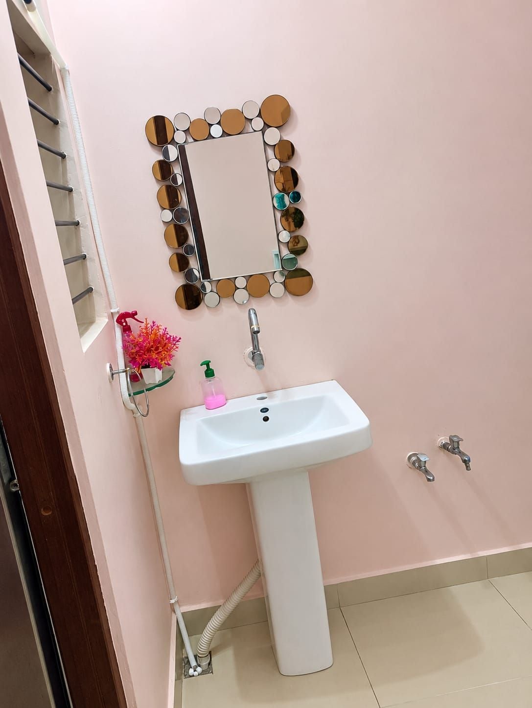 Un baño con un lavabo blanco, un espejo con marco circular y un pequeño estante con dispensador de jabón.
