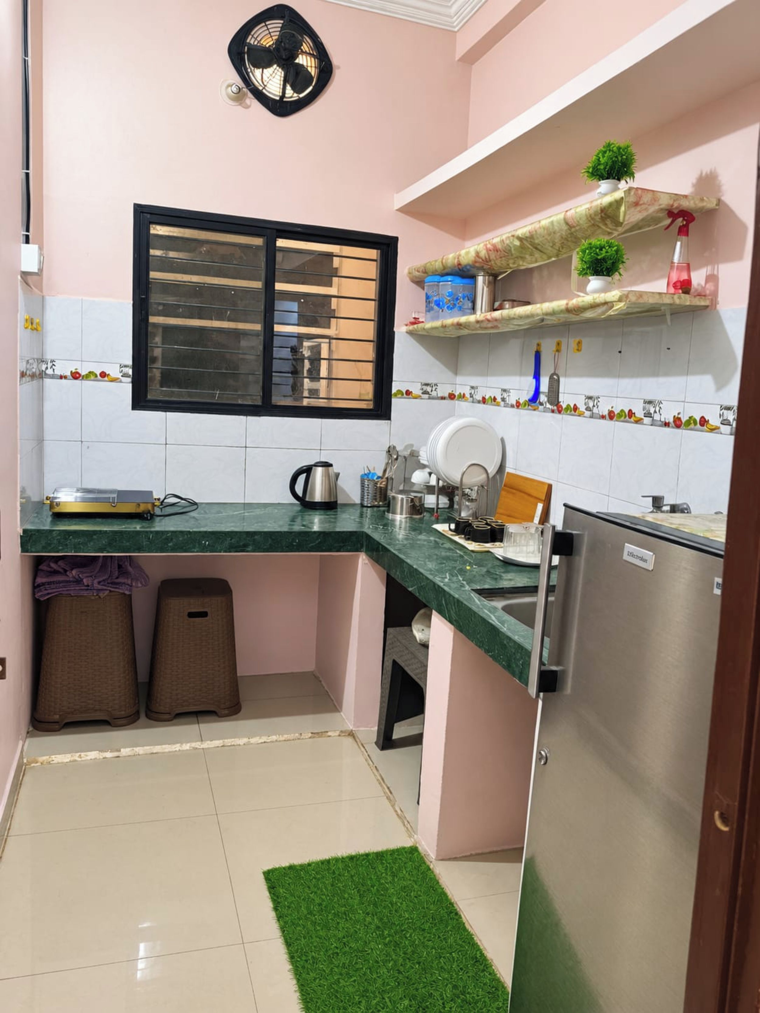 A compact kitchen with a refrigerator, sink, and a window with blinds.