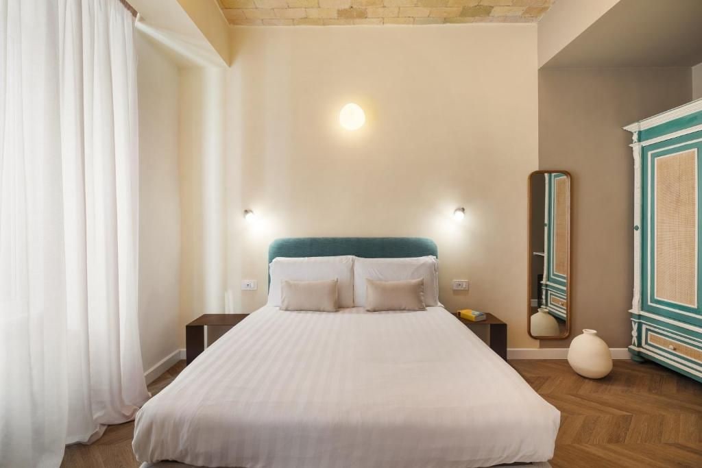 Un dormitorio con cama, mesitas de noche, un espejo y un armario.