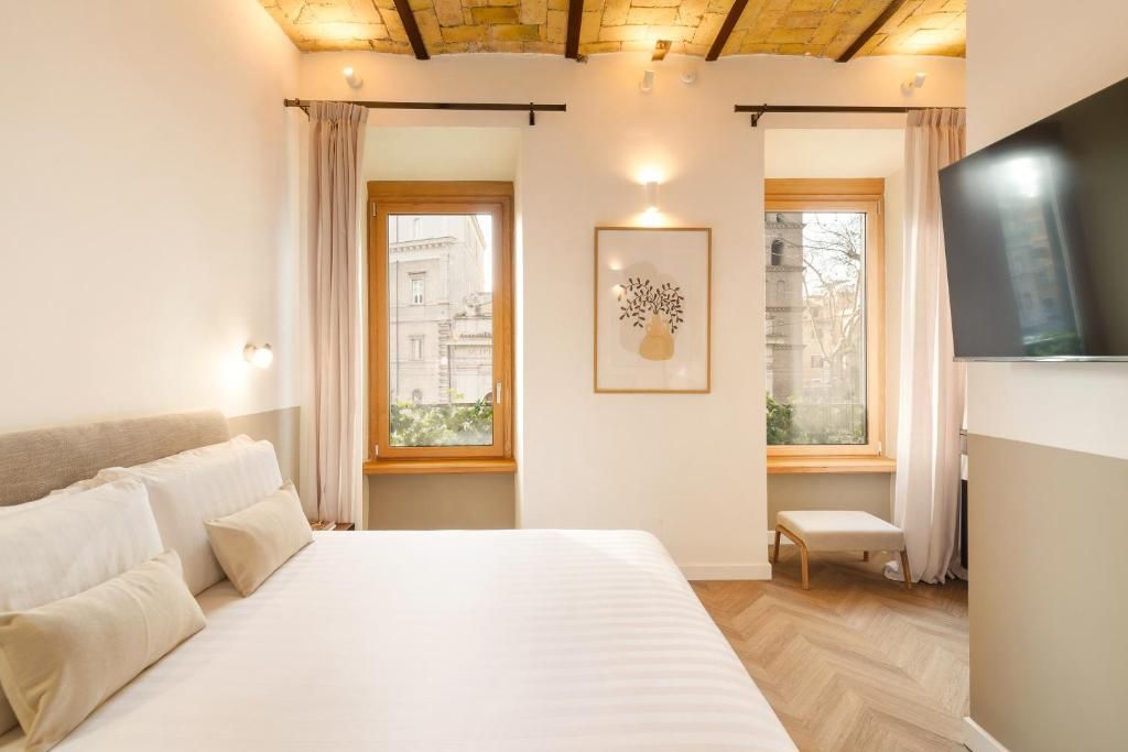 Una habitación de hotel con cama, ventana, un cuadro enmarcado y televisor.