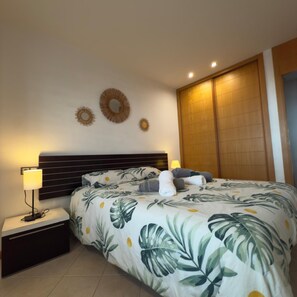 A neatly arranged bedroom with a bed, bedside lamps, a nightstand, and wall decorations. - 3 in Paradise (Adeje)
