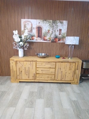 A wooden cabinet with a vase of flowers and a metal bowl on top.