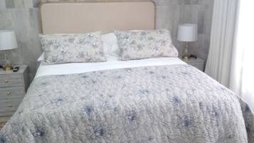 Un lit avec une couvre-lit à motifs floraux, une tête de lit et deux lampes de chevet.