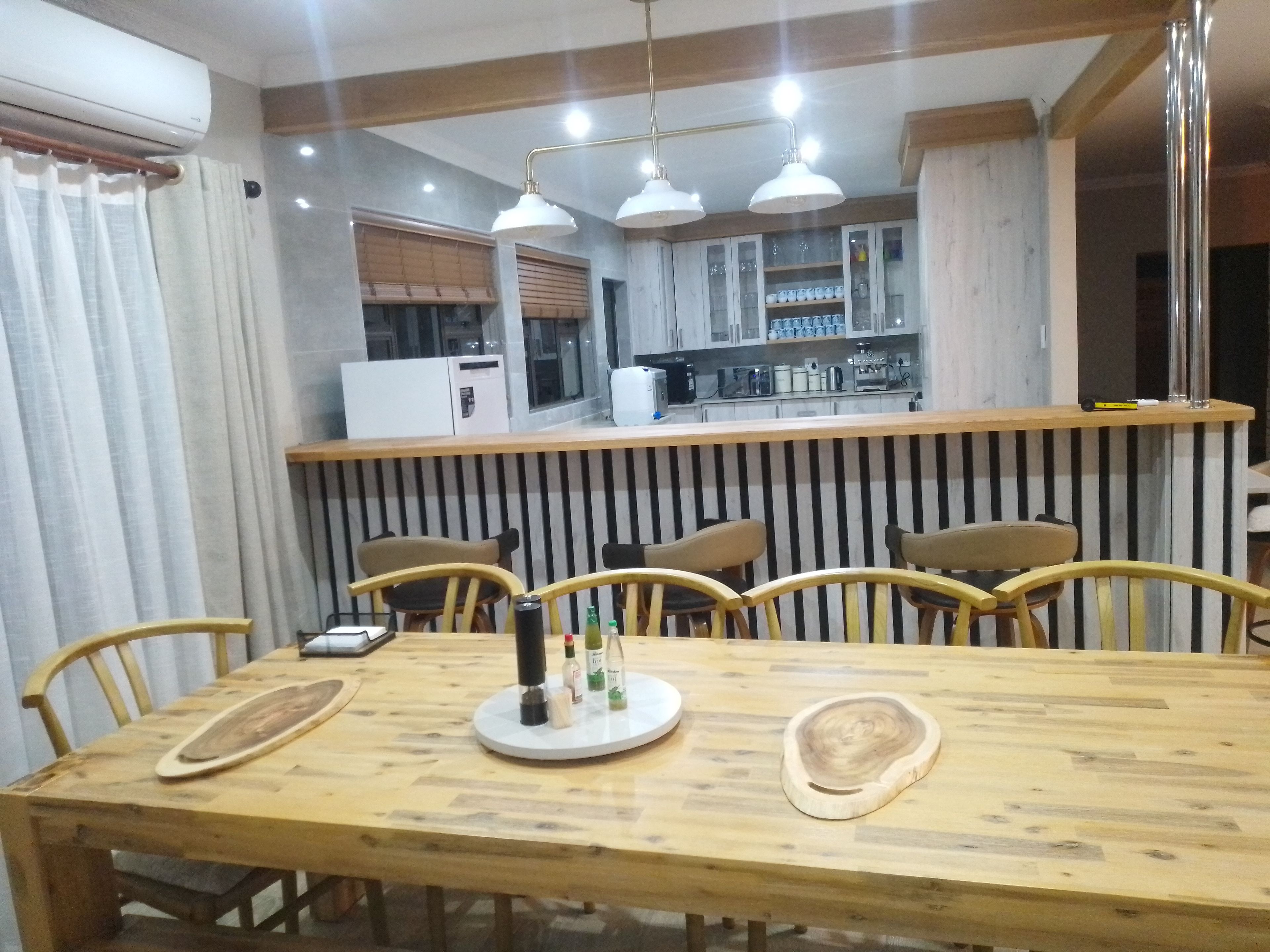 Un coin repas avec une table en bois, des chaises et une cuisine en arrière-plan.
