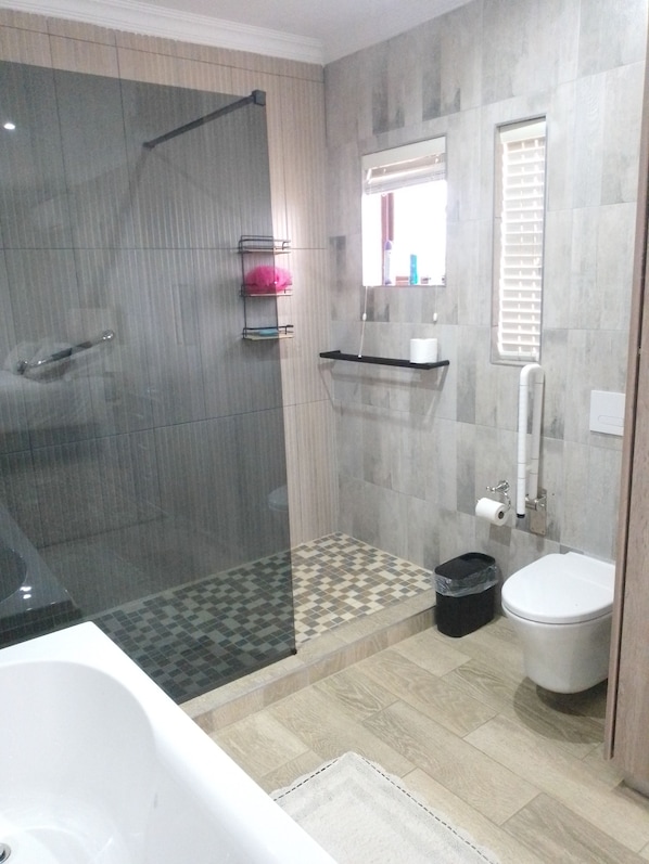 A modern bathroom with a shower, toilet, and bathtub.