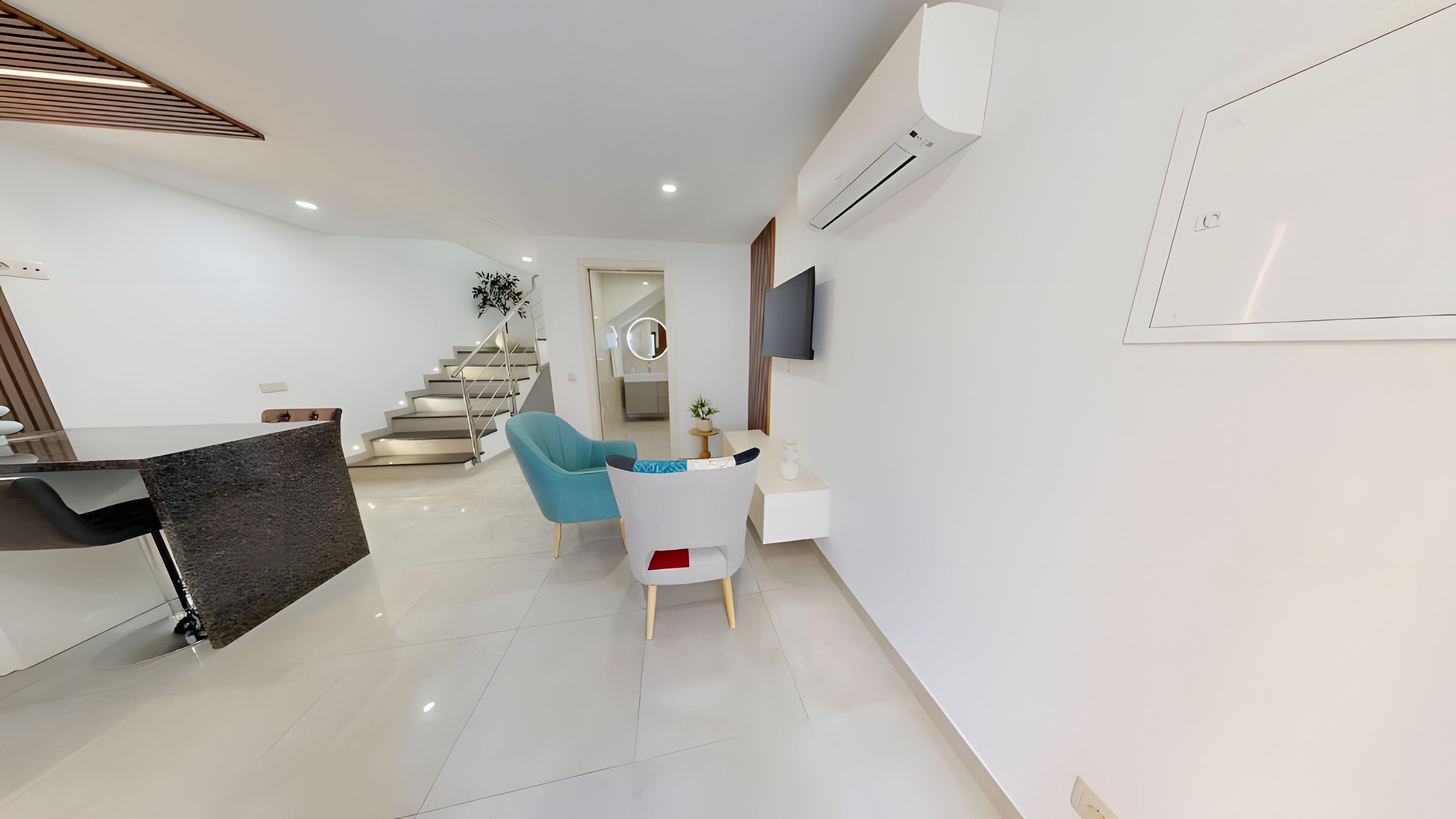Un salon moderne avec un escalier, un téléviseur à écran plat et un coin repas.
