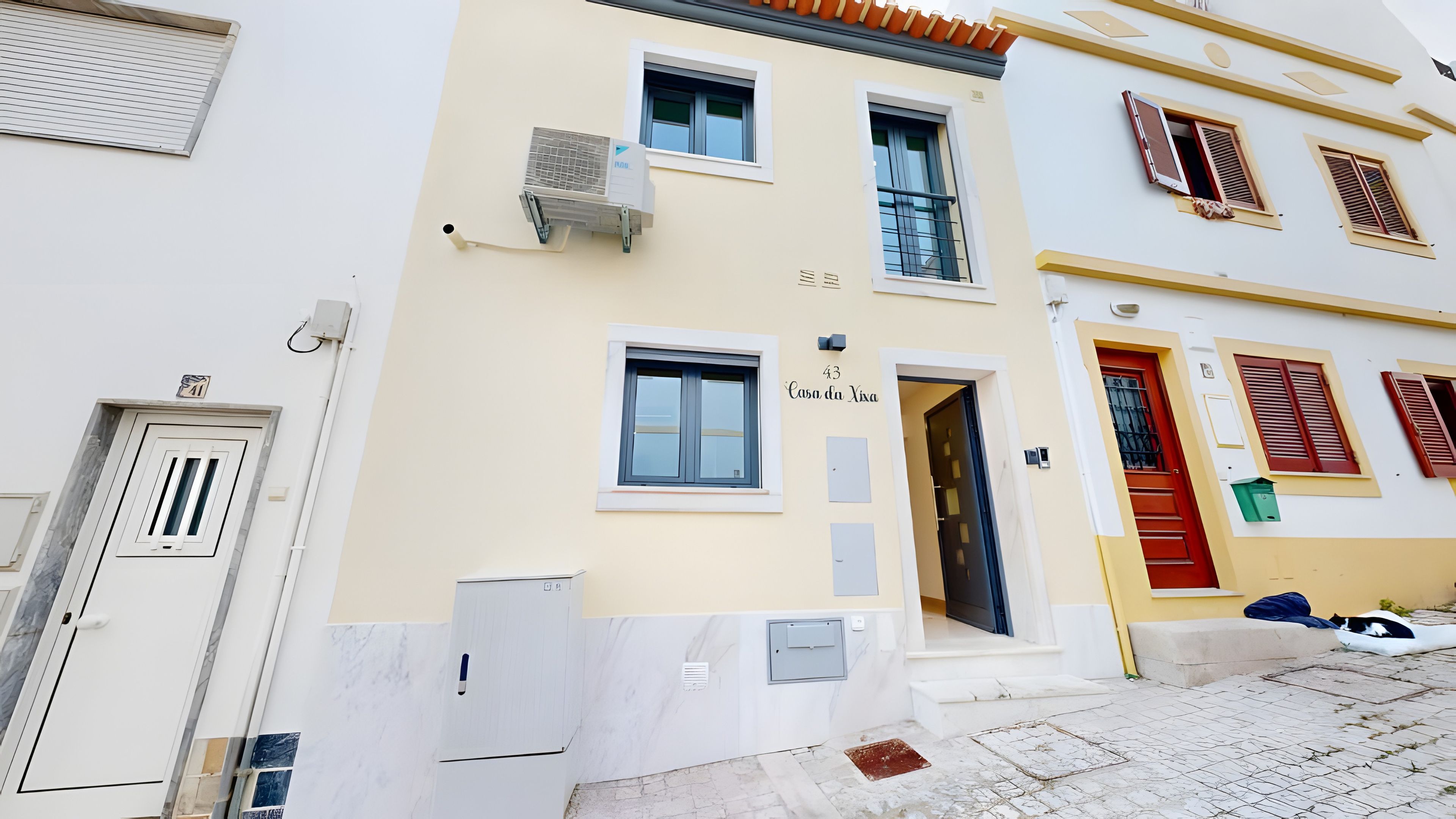 A building with a numbered door, a visible entrance, and a small outdoor area with a trash bin.