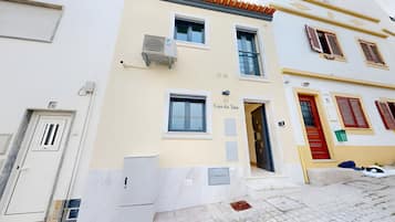 A building with a numbered door, a visible entrance, and a small outdoor area with a trash bin.
