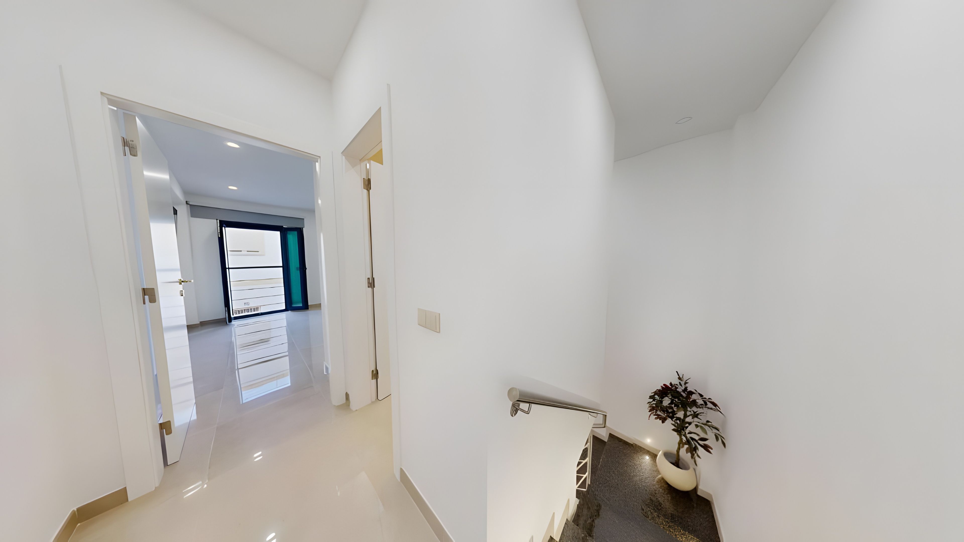 Un interior moderno con un pasillo que conduce a una habitación con un ventanal grande.