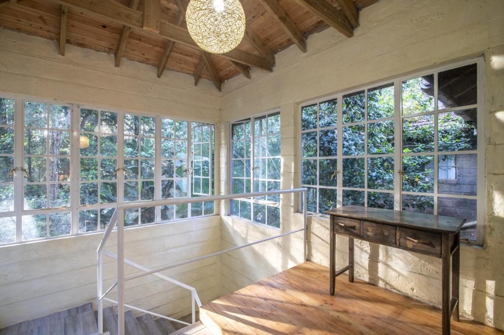 Une pièce dotée de grandes fenêtres, d’un bureau en bois et d’un escalier.