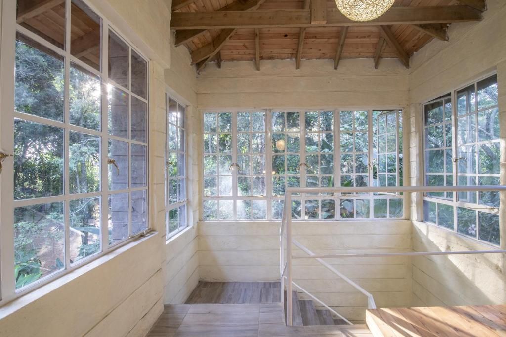 A room with large windows, wooden beams, and a staircase.