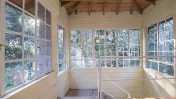 A room with large windows, wooden beams, and a staircase.