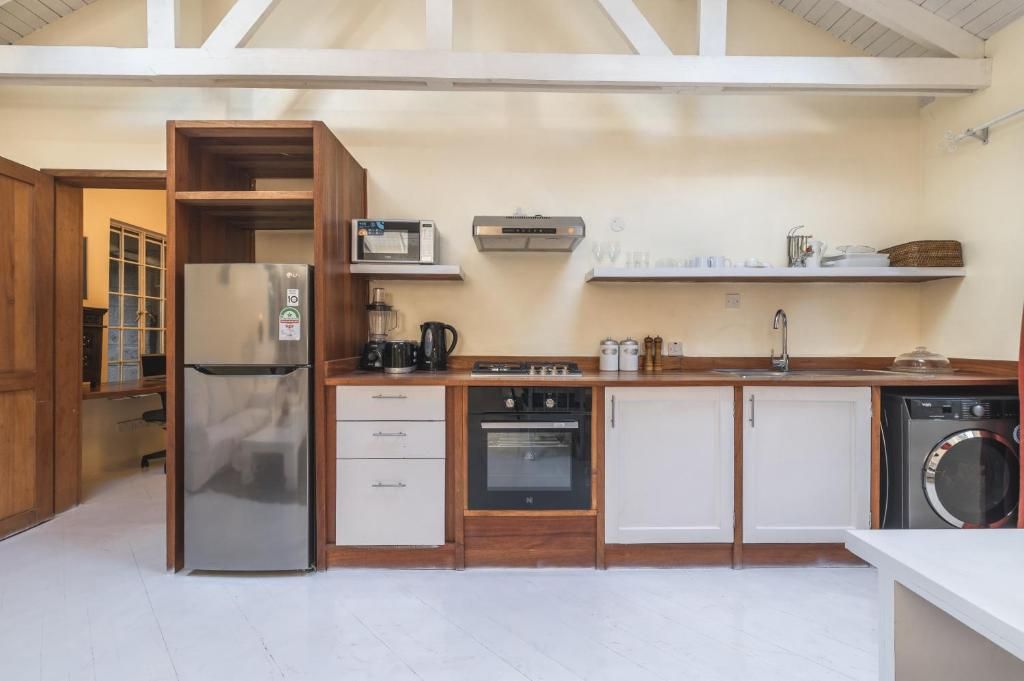 Een functionele keuken met een koelkast, magnetron, oven en wasmachine.