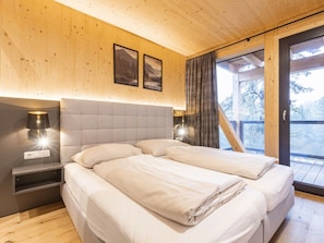 A bedroom with a bed, bedside lamps, and a view of the outdoors. - Superior Chalet # 5 With Sauna & Hot Tub (Stadl-Predlitz)