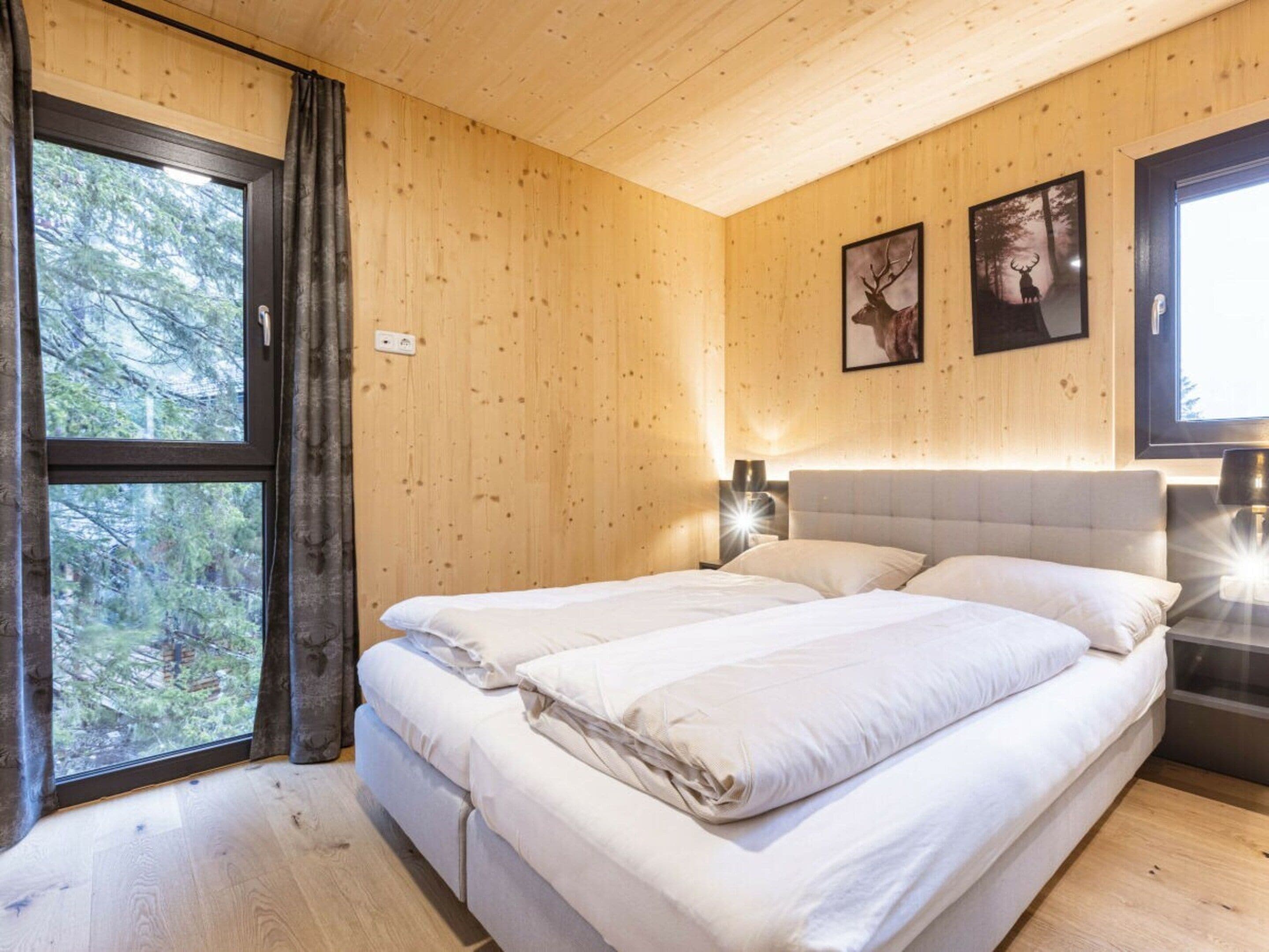 Une pièce comprenant un lit, deux lampes fixées au mur et deux tableaux encadrés.
