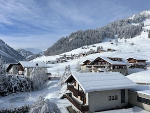 A snow-covered mountain village with chalet-style buildings, a ski slope, and a clear sky. - Vrbo Property (Mittelberg)