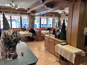 A cozy restaurant with wooden interiors, large windows, and festive decorations. - Vrbo Property (Mittelberg)