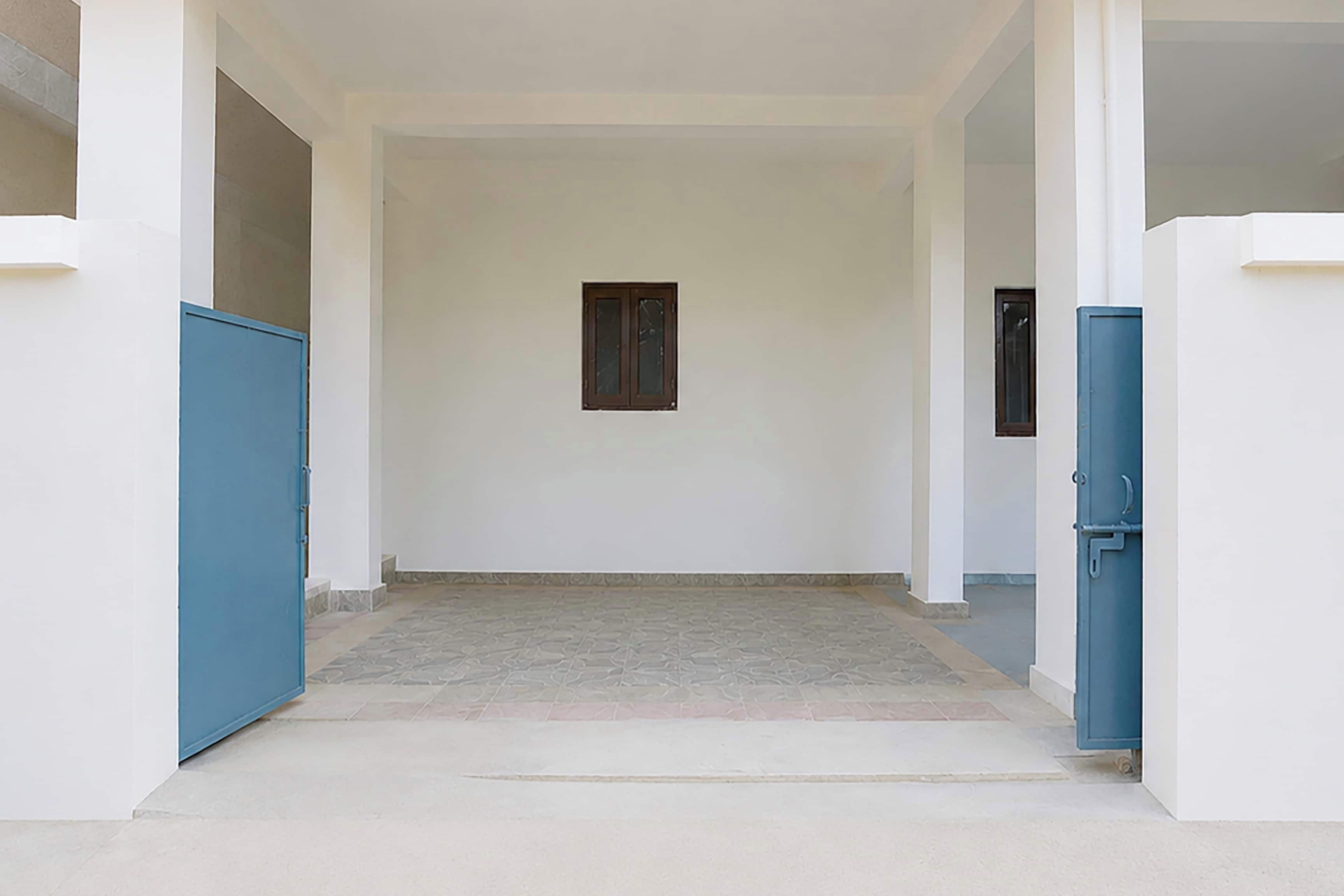 Un pasillo con piso de baldosas, paredes blancas y una única ventana.