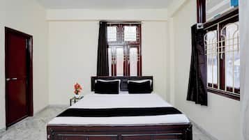 Un dormitorio con cama, ventana con cortinas, radiador y puerta.